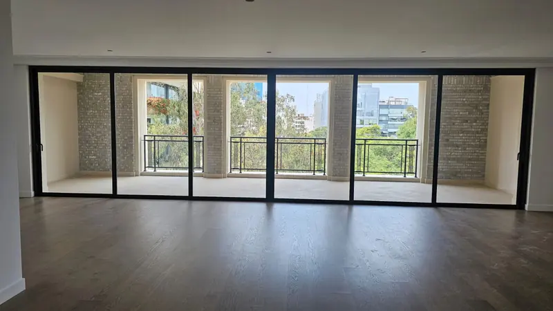Mampara corrediza de vidrio templado con perfilería negra en sala con vista panorámica
