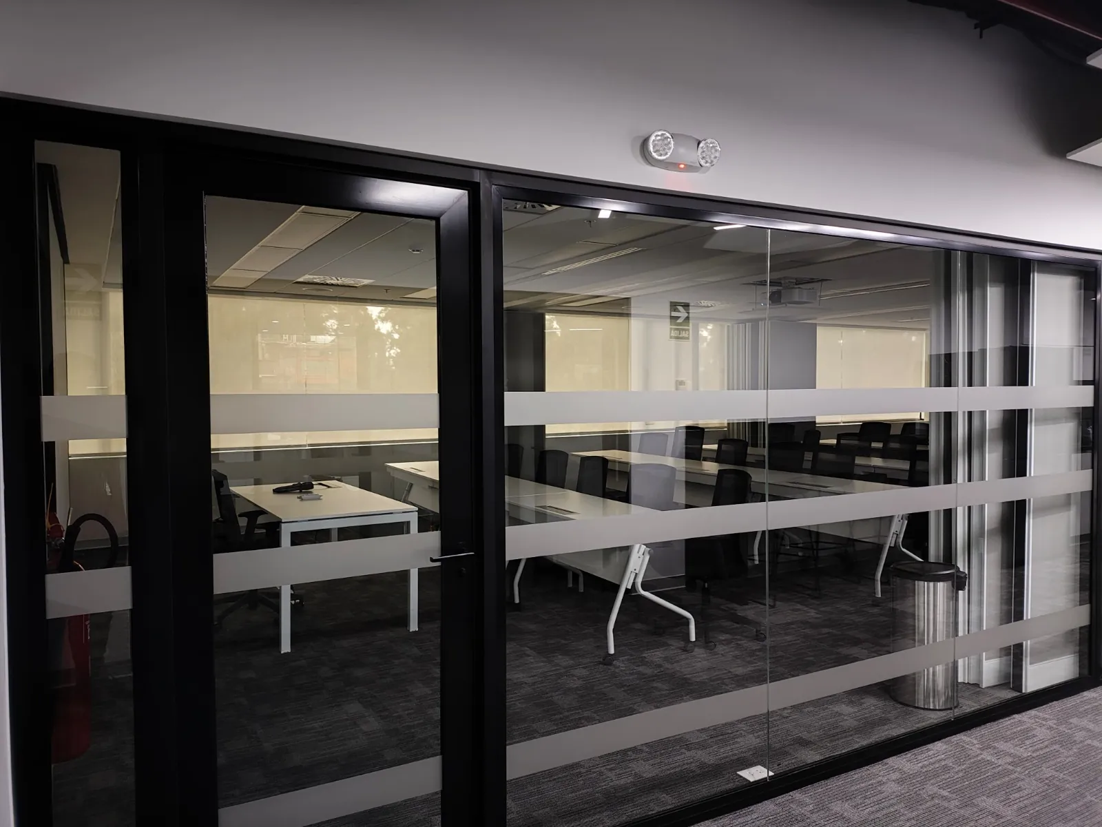 Oficina corporativa con cerramientos de vidrio templado y perfilería negra instalados por Zanabria