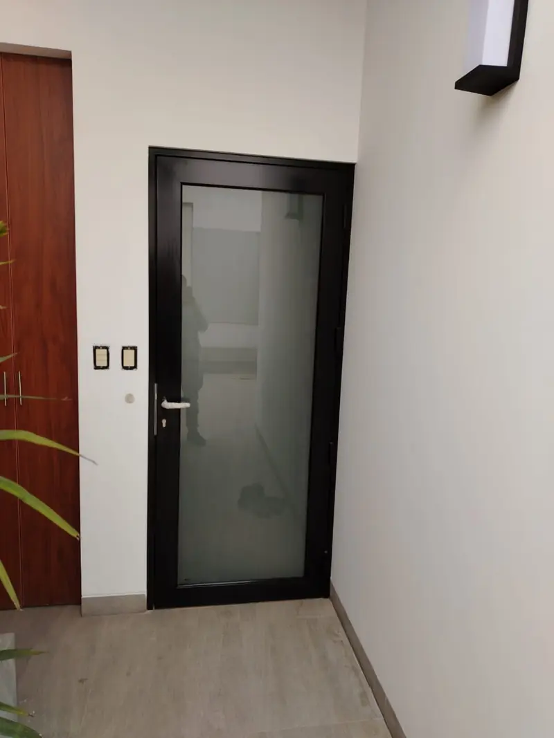 Puerta de vidrio esmerilado con marco de aluminio negro instalada en interior
